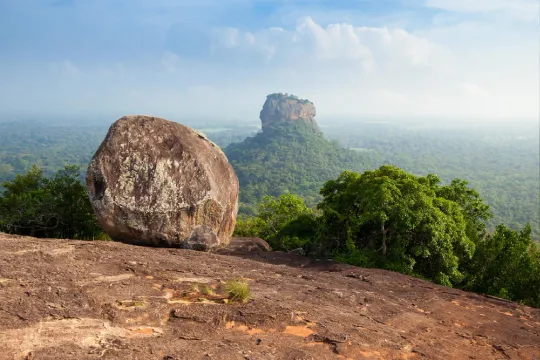 The iconic Lion Rock of Sigiriya, a UNESCO World Heritage Site, majestically rises above the lush greenery, offering breathtaking views from the nearby Pidurangala Rock.